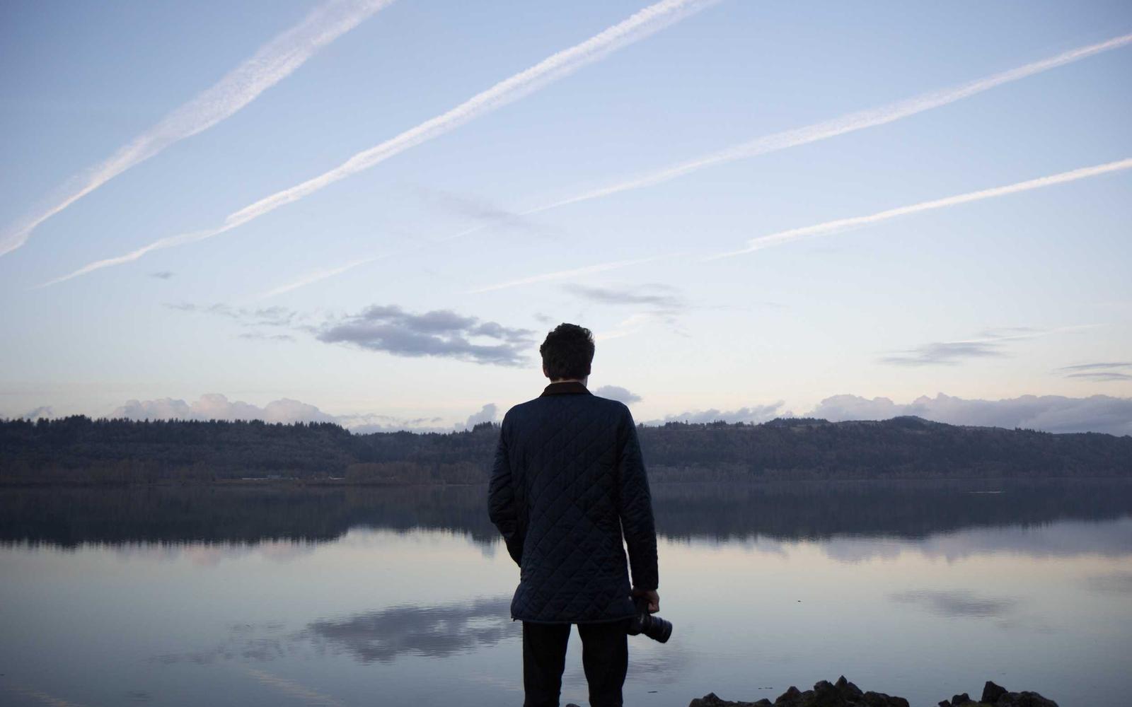 Phone held at arm's length, UI blurred except for a single highlighted button in thumb reach